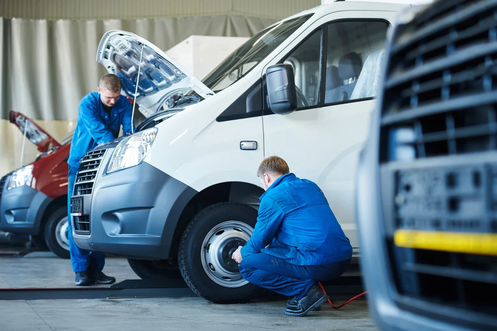 Two mechanics work on a fleet of vehicles to connect IoT devices